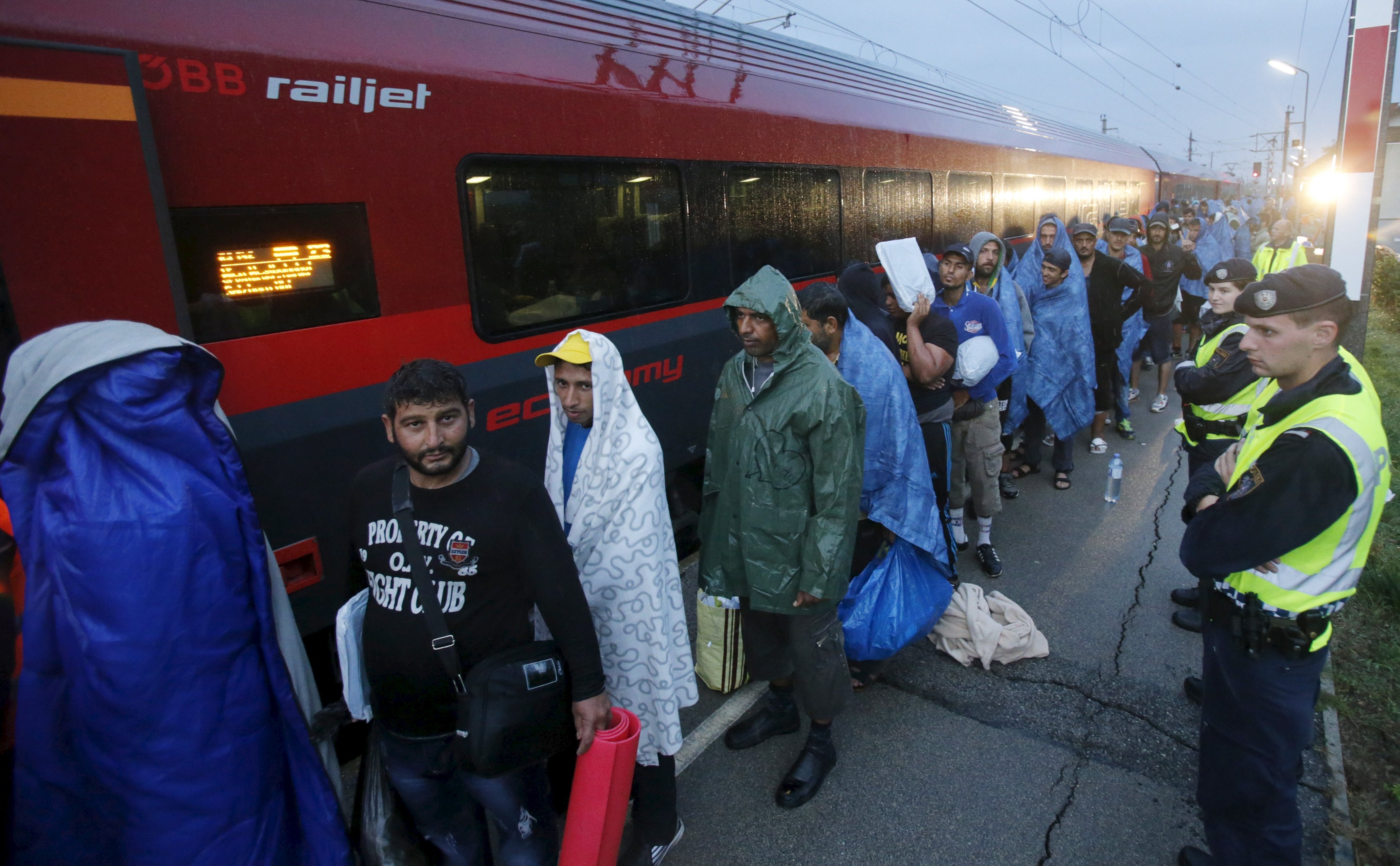 Migrants arrive at the Austrian train station of Nickelsdorf to board trains to Germany, September 5, 2015. Hundreds of exhausted migrants streamed into Austria on Saturday, reaching the border on buses provided by an overwhelmed Hungarian government that gave up trying to hold back crowds that had set out on foot for western Europe.   REUTERS/Heinz-Peter Bader